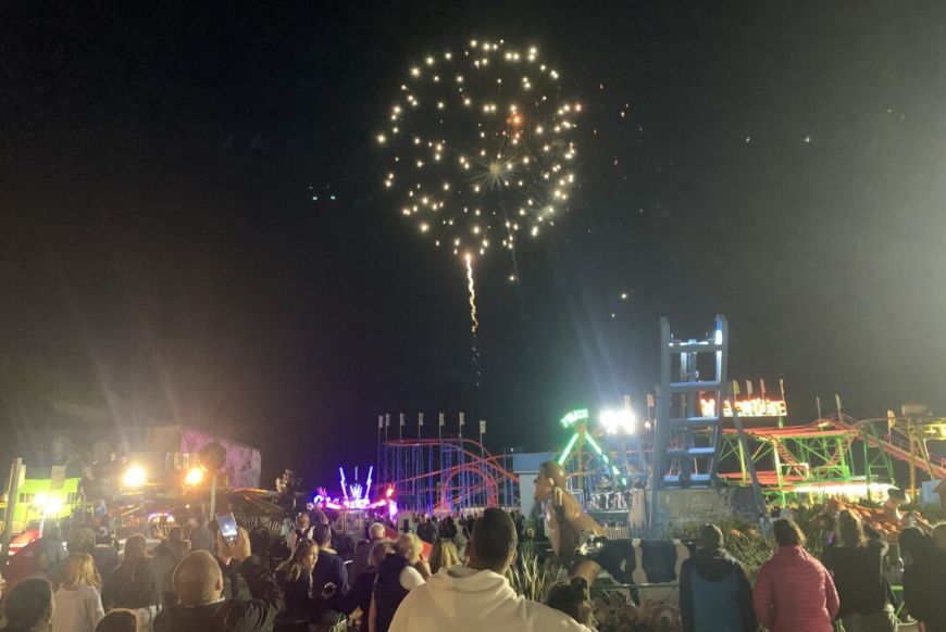 people in a theme park watching a firework in the sky